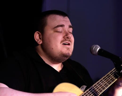Grégoire chante en s'accompagnant à la guitare.